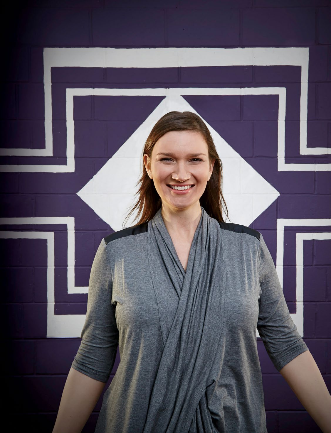 An image of Samantha Leonard standing in front of a brick wall. The brick wall has a simple pattern drawn on it.