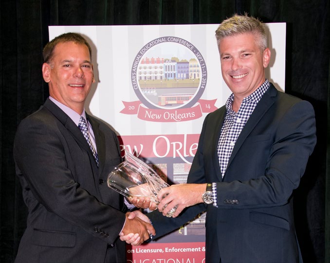 A photo of College Registrar and CEO Michael Salvatori accepting the 2014 CLEAR Regulatory Excellence award from CLEAR Past President Darrel Crimmins.