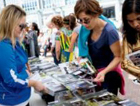 A photo of College staff holding a magazine up. There are two people looking at the magazine.