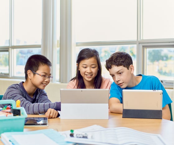 A photo of Yvonne Sun-Hsu helping a student with a laptop. There are two other students nearby working on laptops.