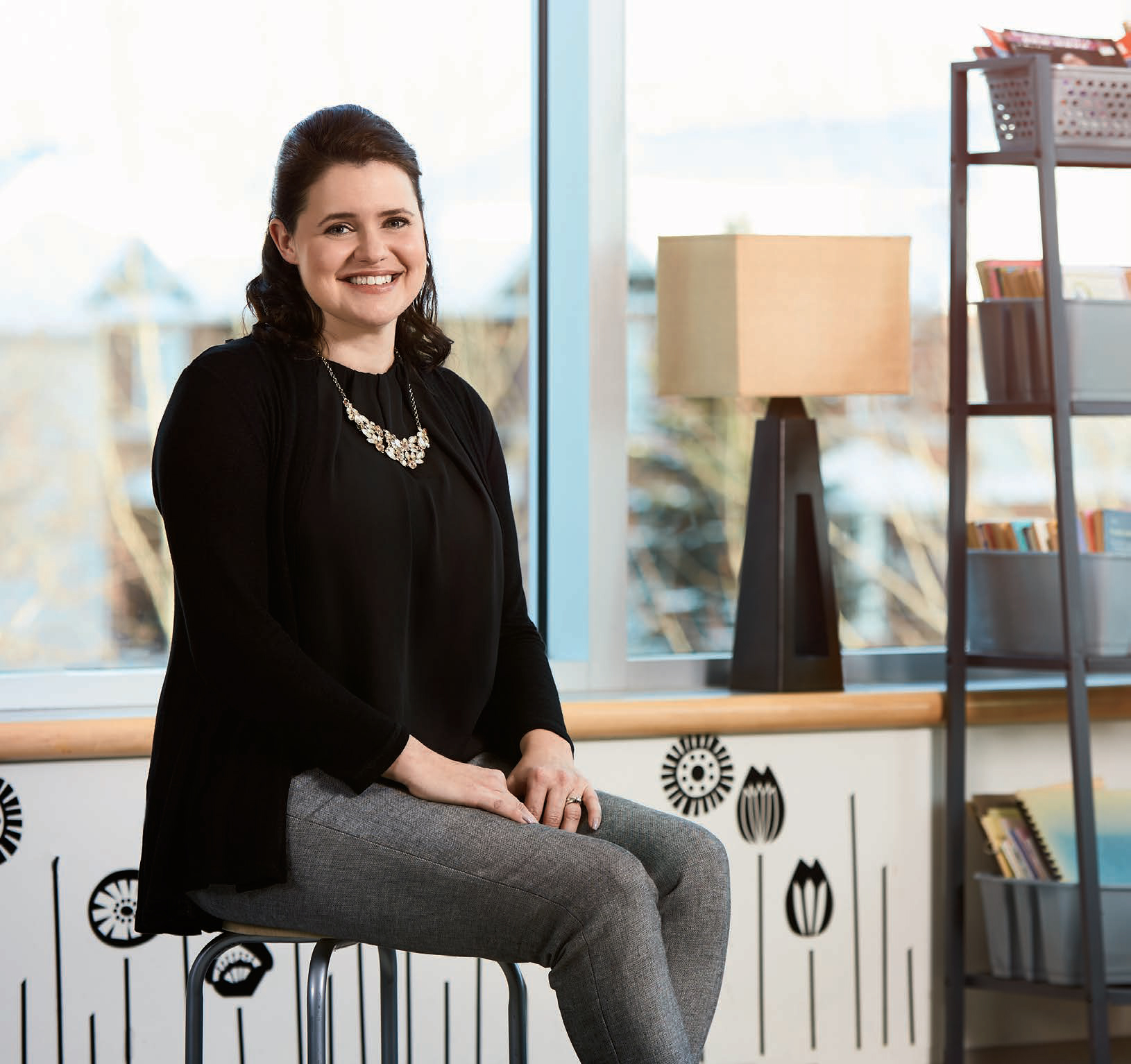 A photo of Tracey Tinley, Ontario Certified Teacher, sitting in a chair and smiling with hands in lap.