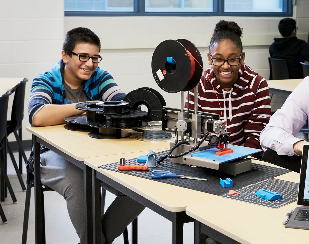 A photo of teenaged students working with a 3D printer.