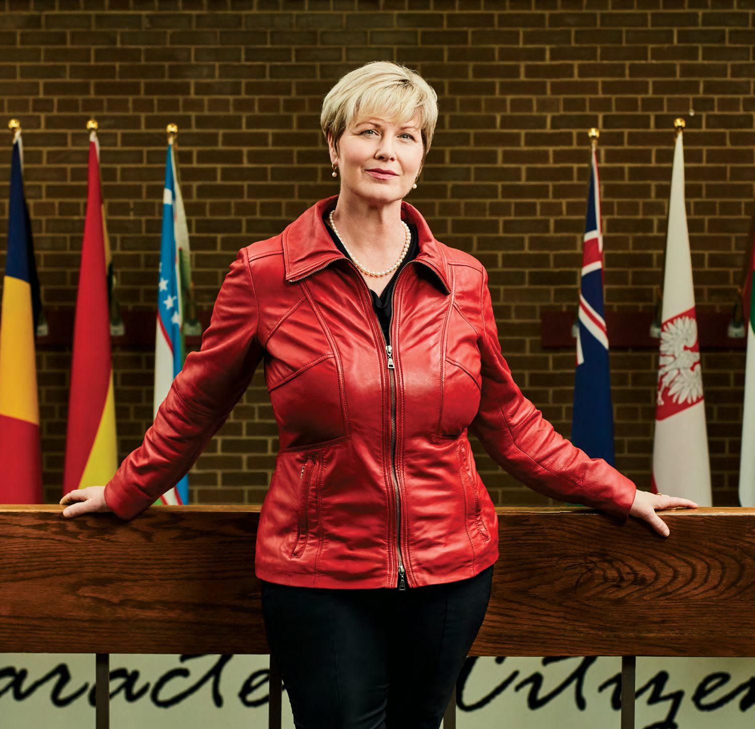 Andrea Taylor, Ontario Certified Teacher, standing in front of the flags of several different nations.