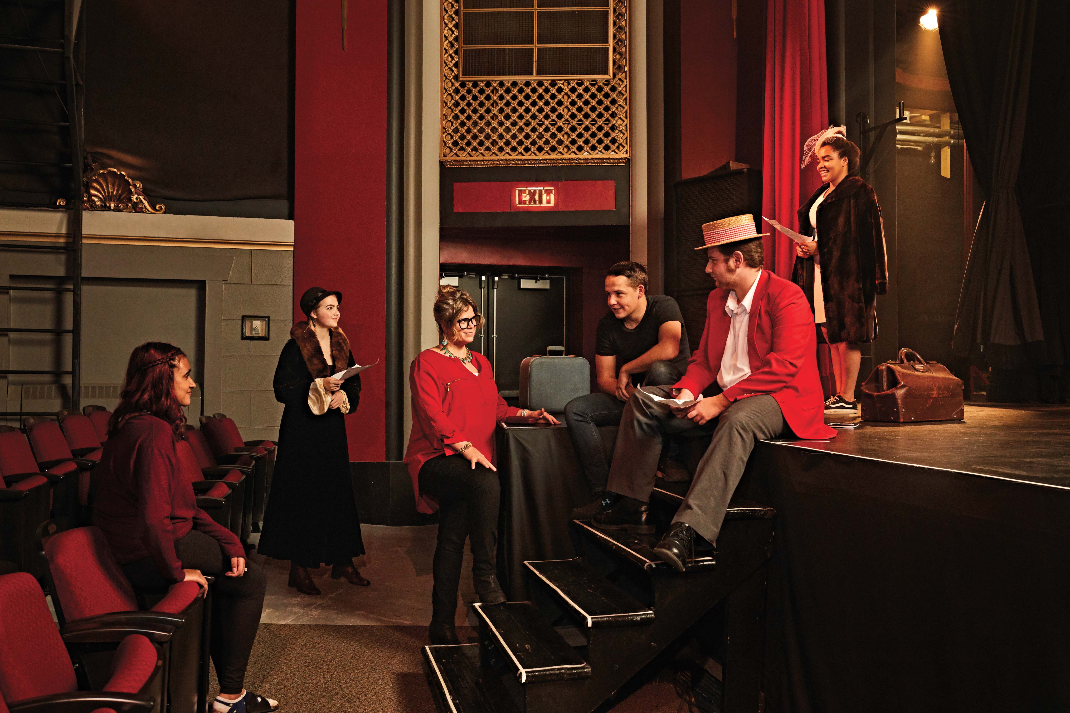 Photo of Jessica Kennedy, Ontario Certified Teacher, in a theatre with students dressed in costumes around and on a stage.