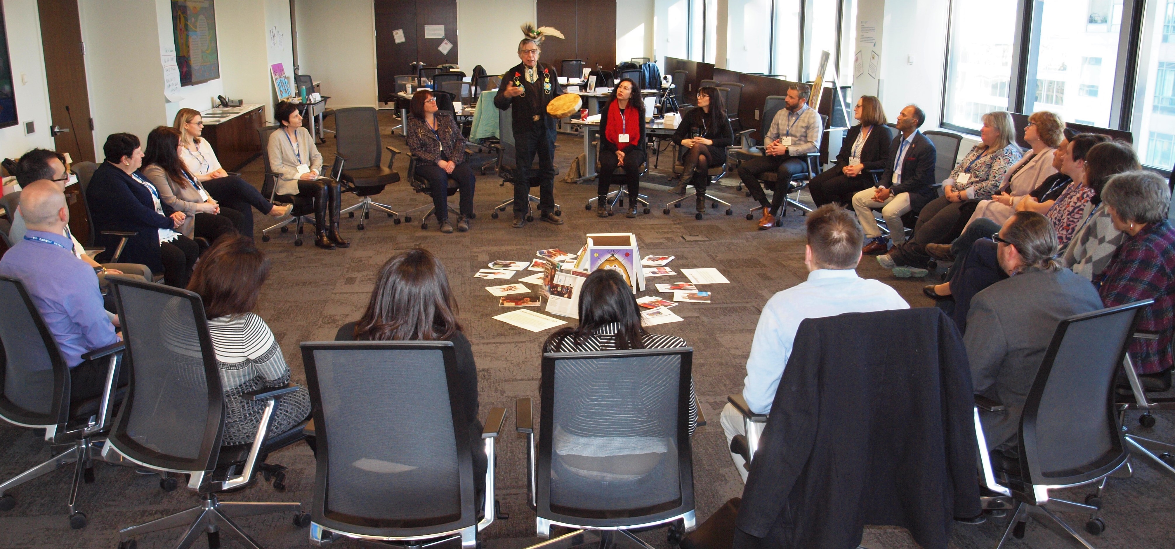 Photo of a group of educators seated in a circle watching a demonstration.