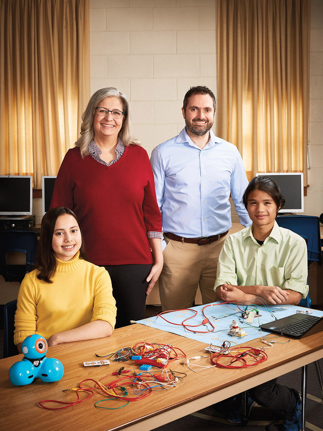 Photo of Donna Foster, Ontario Certified Teacher and Luigi Sorbara standing behind two seated students.