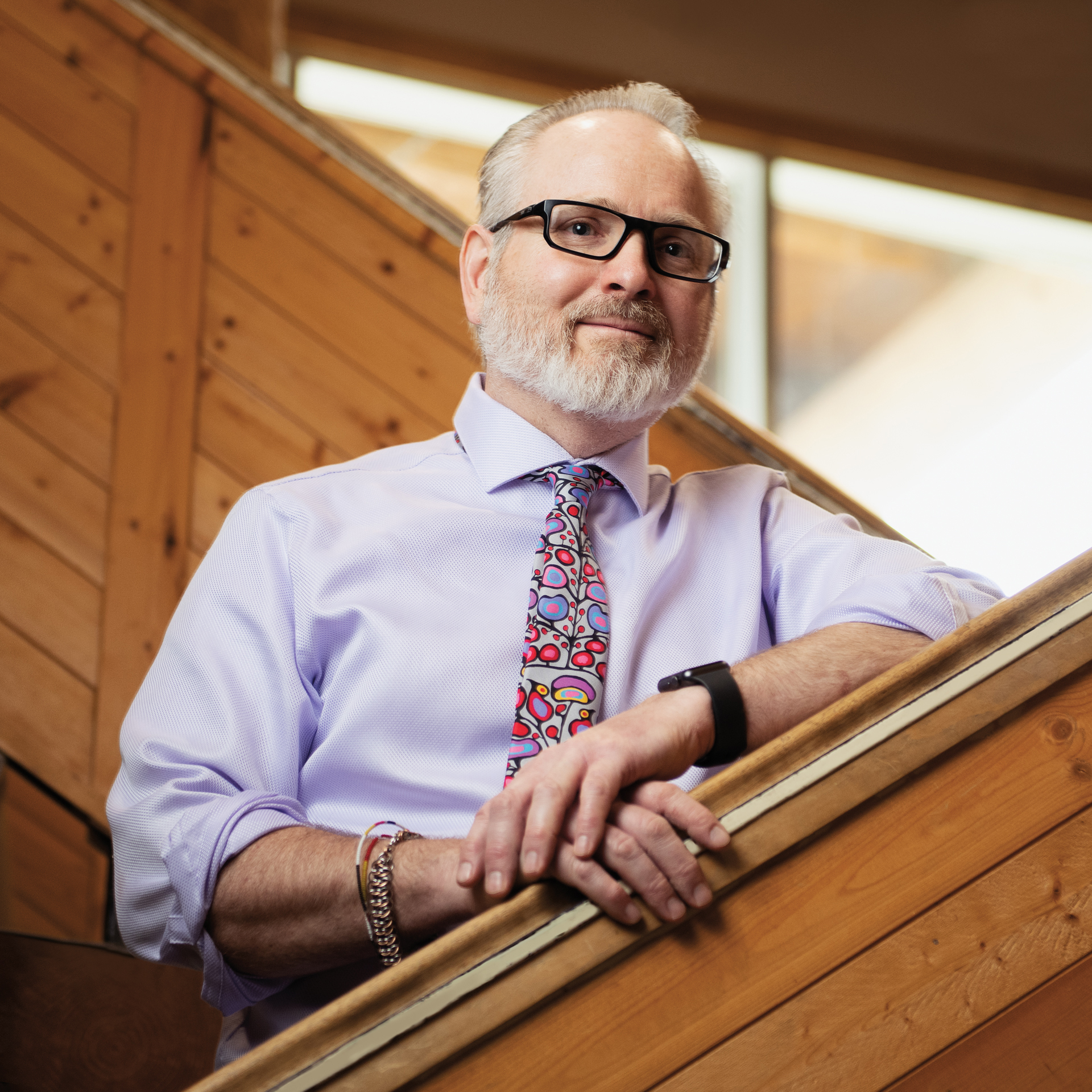 Photo of Chris Mara, Ontario Certified Teacher, smiling while resting along a wooden banister. 