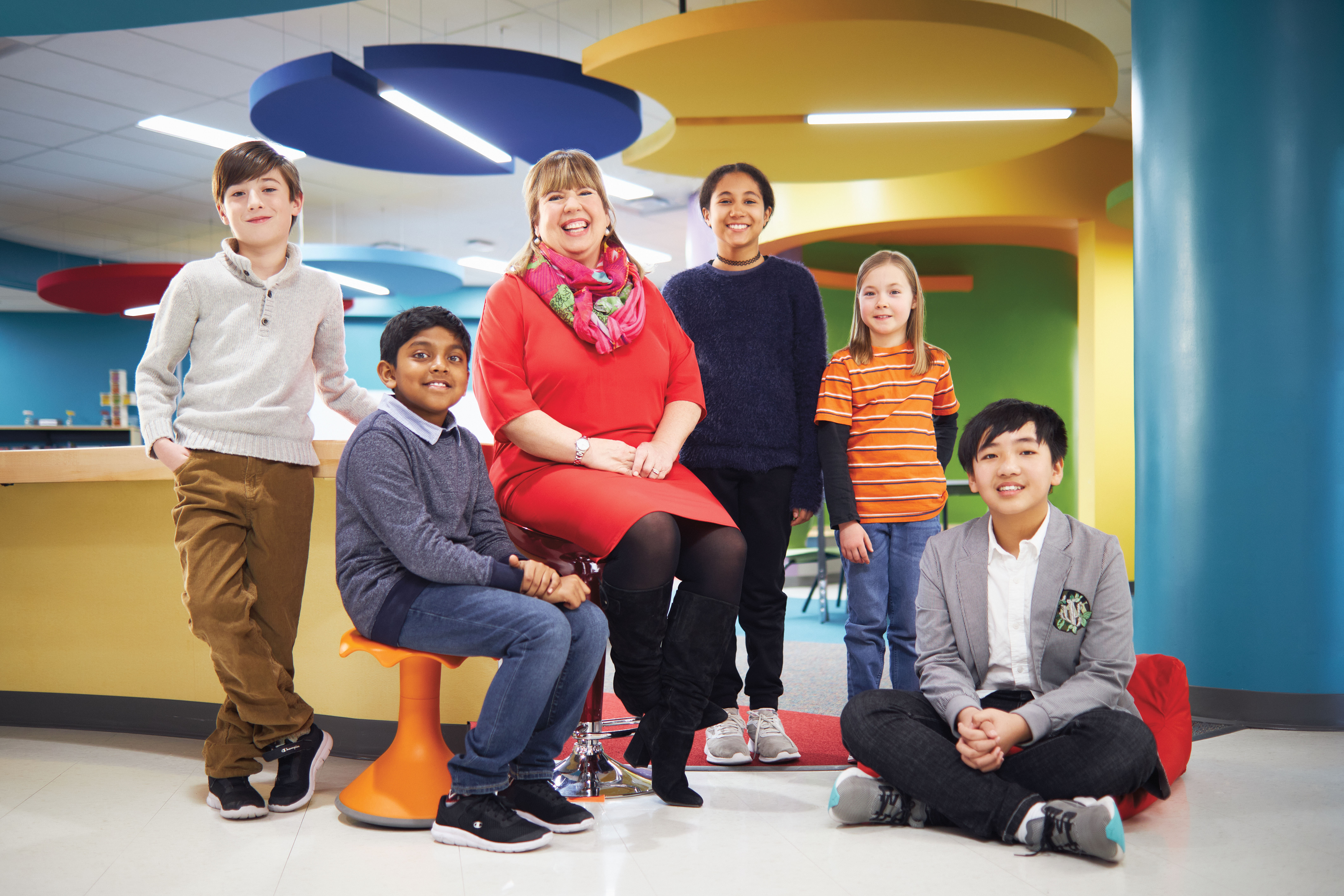 Photo of Lynne Charette, OCT, sitting and smiling. Lynne is surrounded by a group of smiling children.