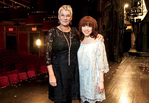 An image of retired teacher Beverley Holmes standing on a stage with Carly Rae Jepsen. Beverly has her arm around Carly.