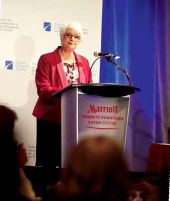A photo of Ontario Education Minister Liz Sandals standing at a podium during the College's  ""Inspiring Public Confidence"" conference.