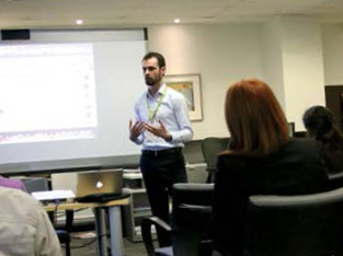 A photo of author and lawyer Dustin Milligan standing in front of a room delivering a presentation.