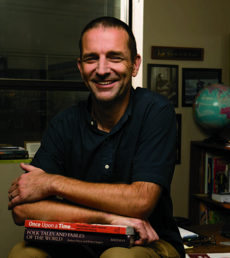 Photo of Brad Woods, Ontario Certified Teacher, leaning on a stack of books.