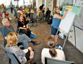 A College employee writing on a board in front of a crowd