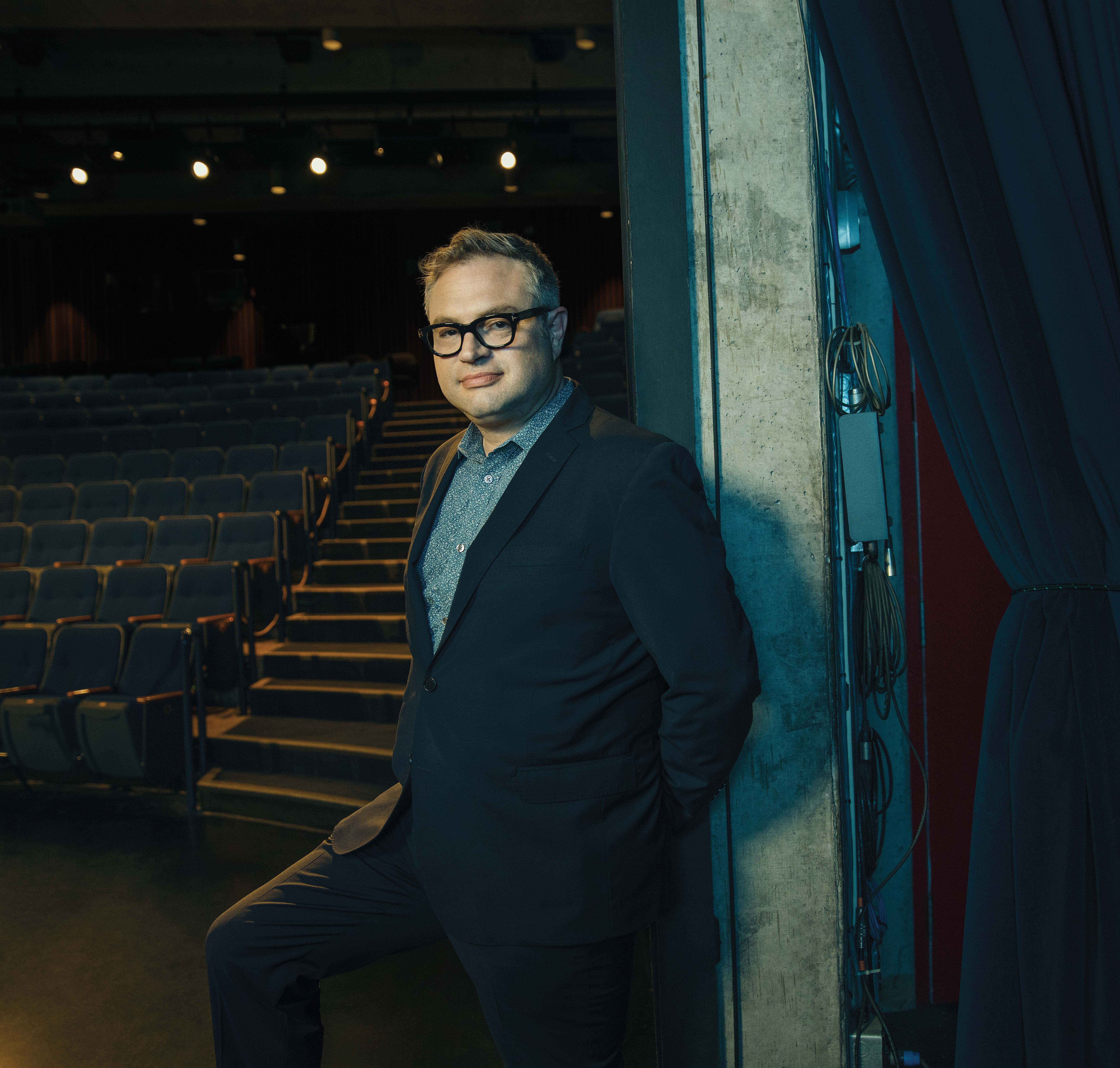 Photo of Steven Page, Canadian music icon, leaning against a wall in a theatre. 