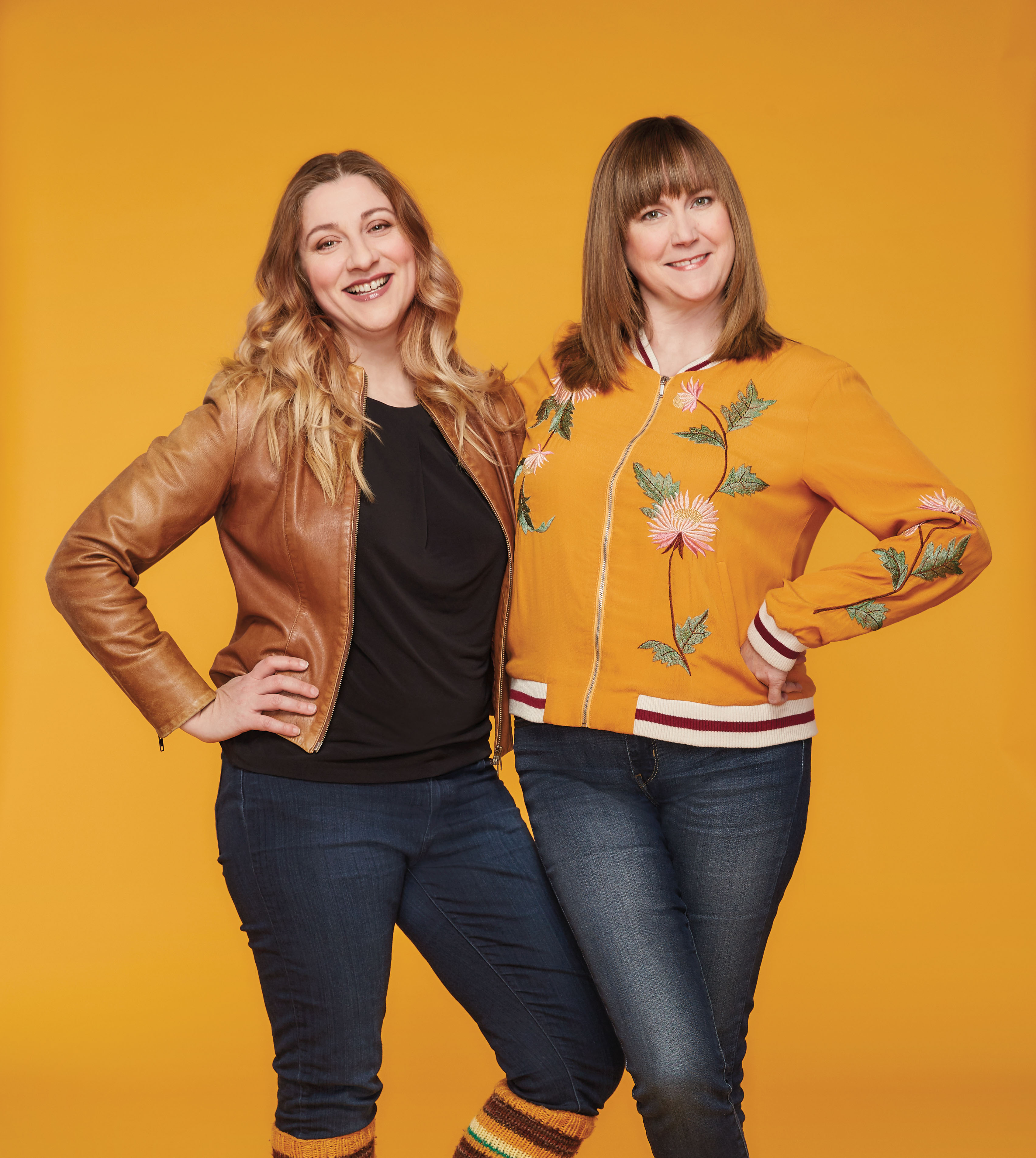 Photo of Baroness von Sketch Show's Aurora Browne and Jennifer Whalen smiling and posing with their hands on their hips.
