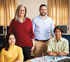 Photo of James Pedrech, Ontario Certified Teacher, standing behind two seated students.