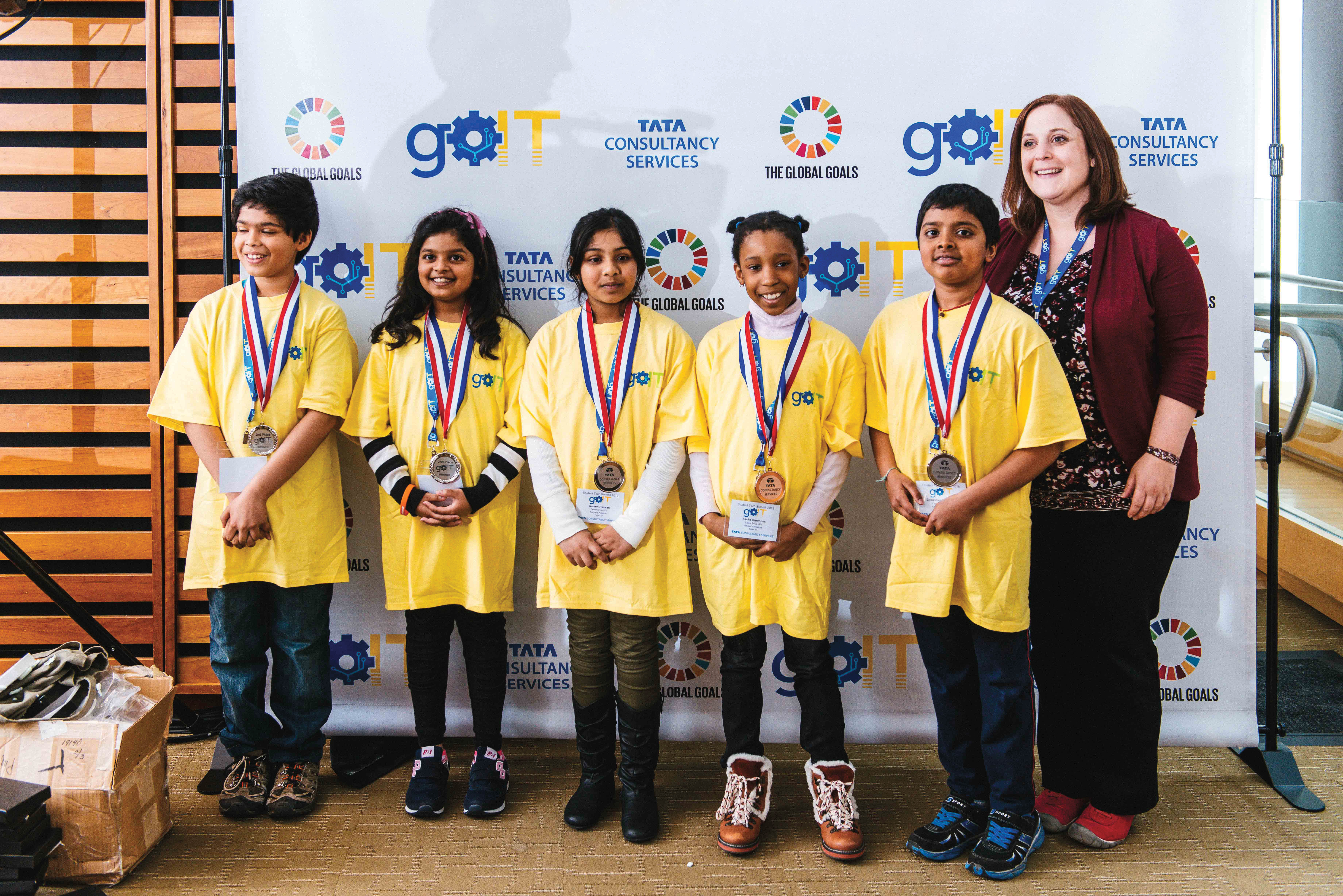 Photo of Laura Kerpel, OCT, a Grade 3 teacher at Cedar Drive Junior Public School, smiling with students who are wearing award medals around their necks.