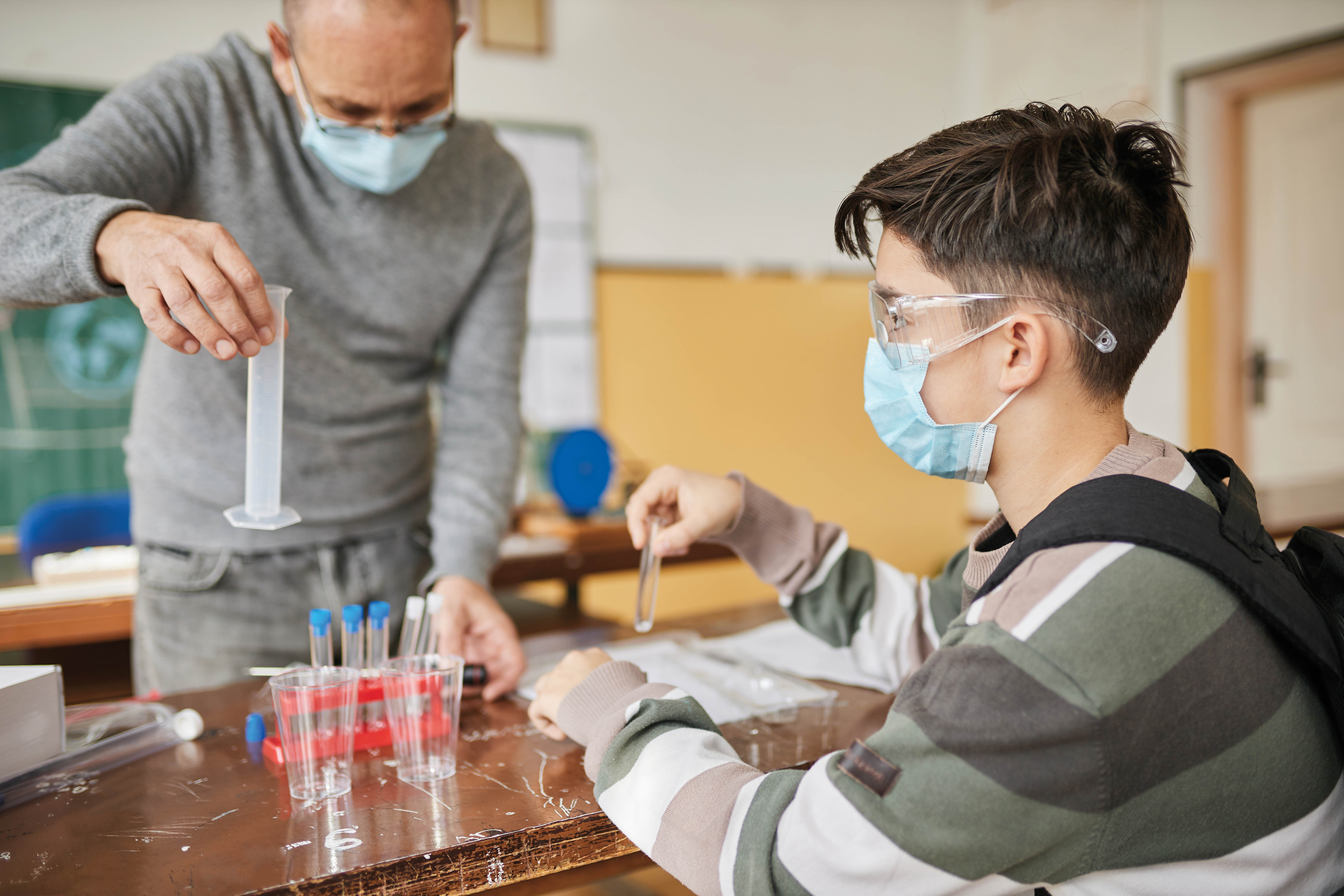 A student and teacher working in a chemistry lab.