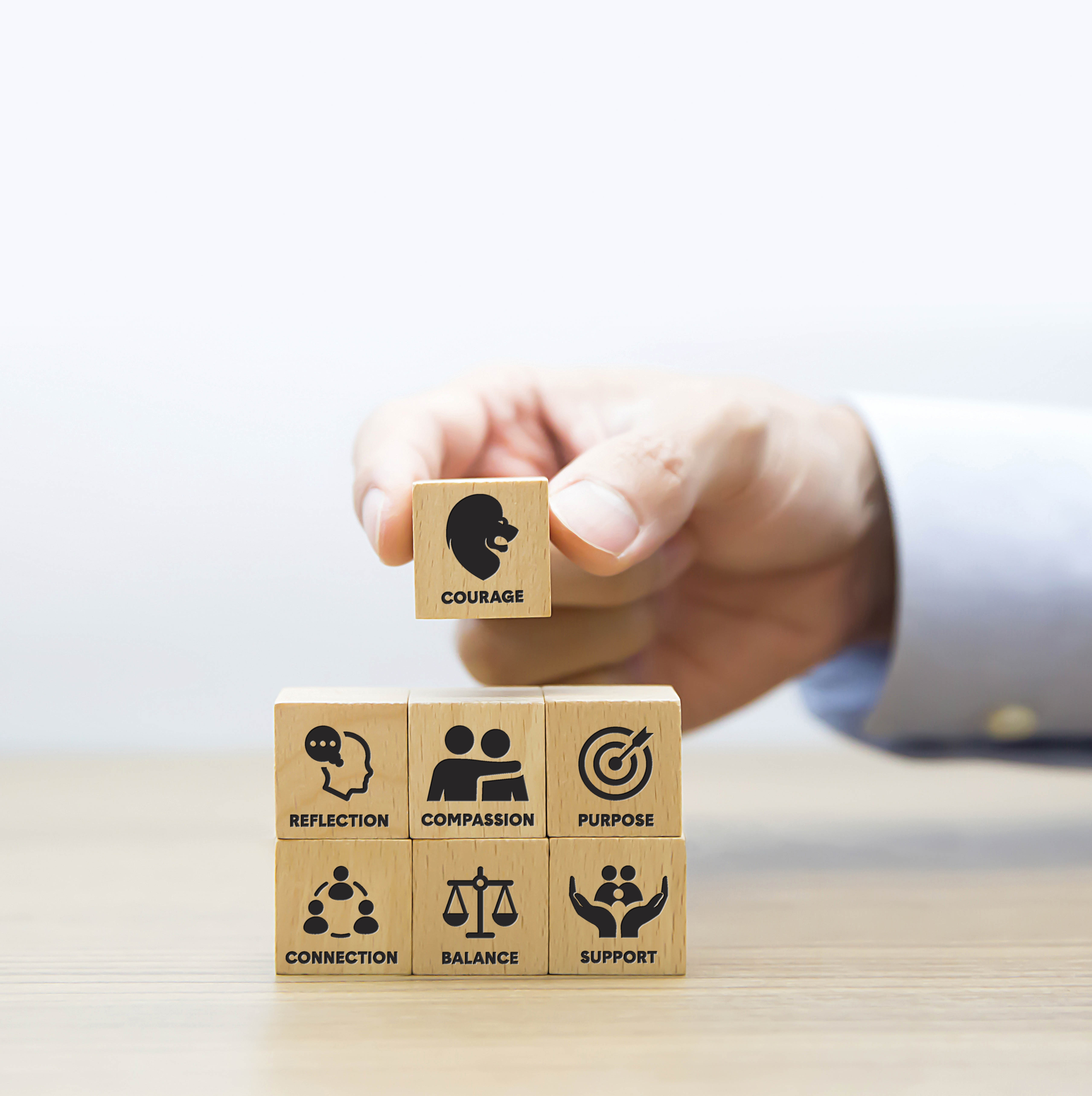 Hand placing wooden block on stack of blocks.
        